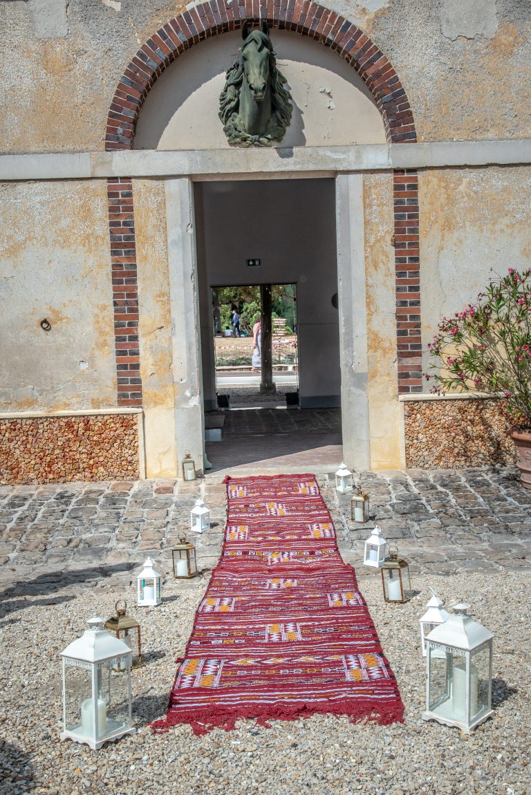 Entrée de la salle du mariage avec un tapis oriental longé par des luminaire champêtre