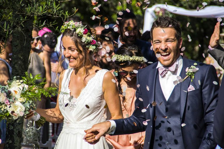 Mariés heureux sortant de leur cérémonie laïque sous une pluie de confettis, entourés d'invités souriants.