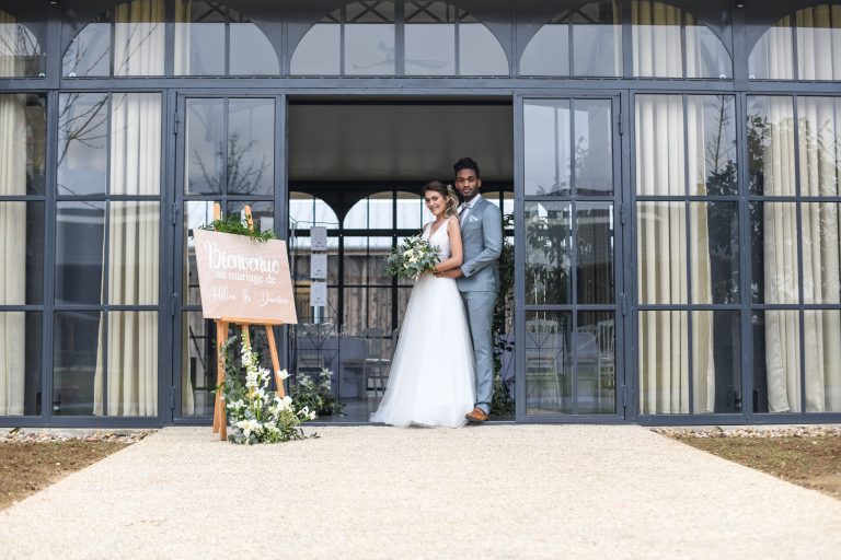 Le couple prenant la pose devant l'entrée du lieu de réception