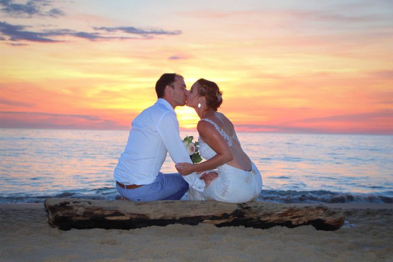 photo des mariés au bord de la mer avec le coucher de soleil