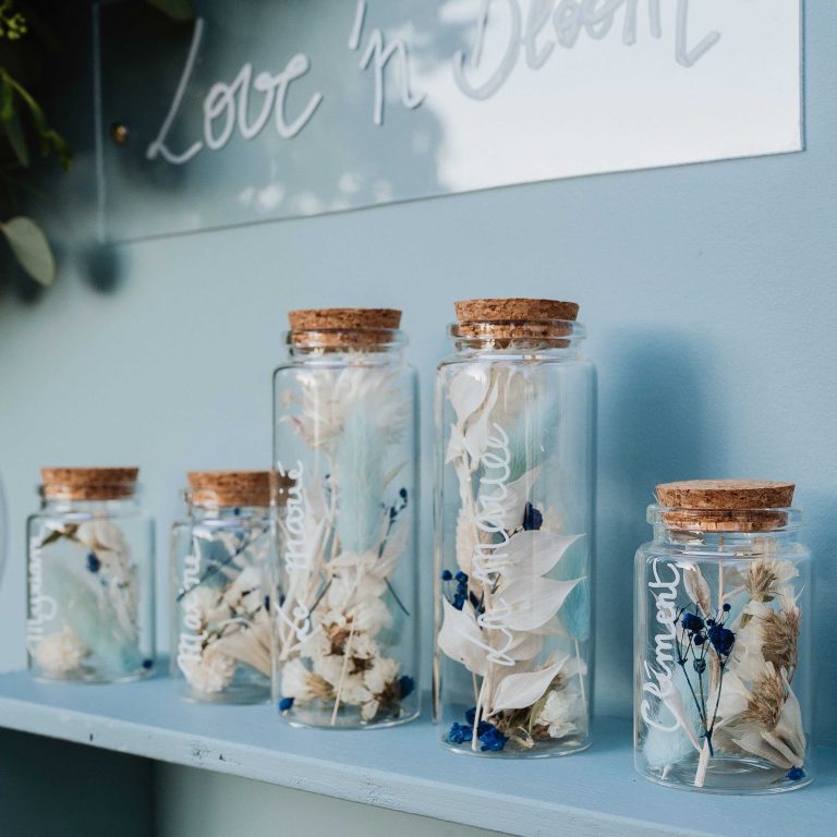 Vase avec fleurs blanche dedans refermé par un bouchon en liège sur un mur en fond bleu