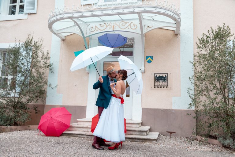 couple devant un porche en train de s'embrasser avec des parapluies