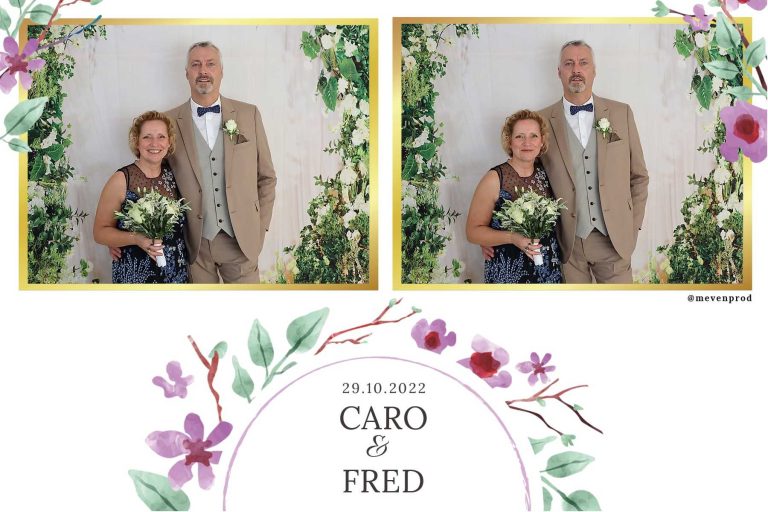 Caro et Fred souriants devant un fond floral lors de leur célébration de mariage le 29.10.2022.