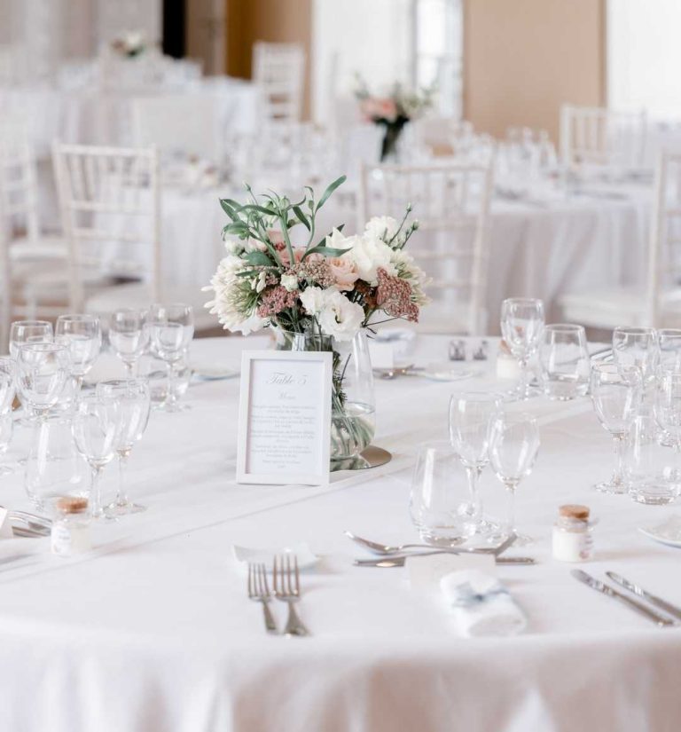 Décoration élégante de table de mariage avec bouquet central et menus.