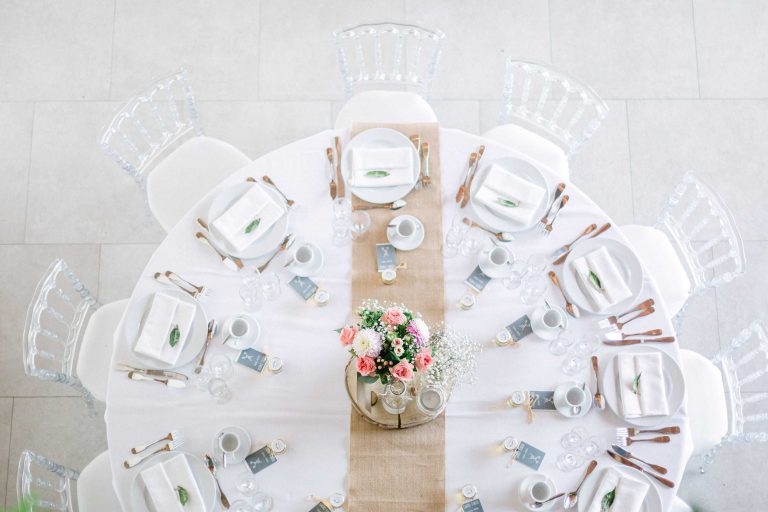 Vue aérienne d'une table de mariage élégante avec chaises transparentes et décoration florale.