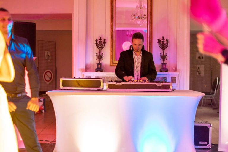 DJ derrière ses platines qui mixe pour un mariage avec des lumières violette