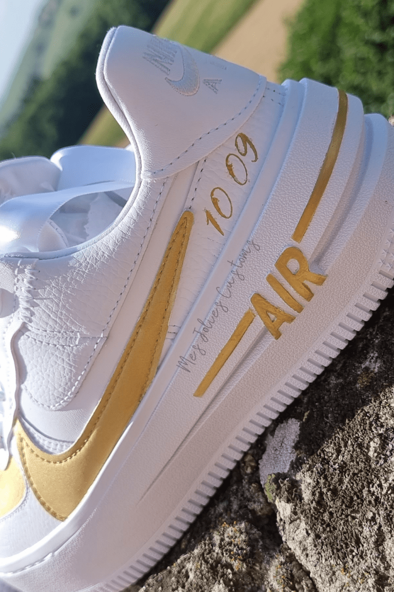 Sneakers de mariage blancs et dorés avec date personnalisée, posés sur un rocher.