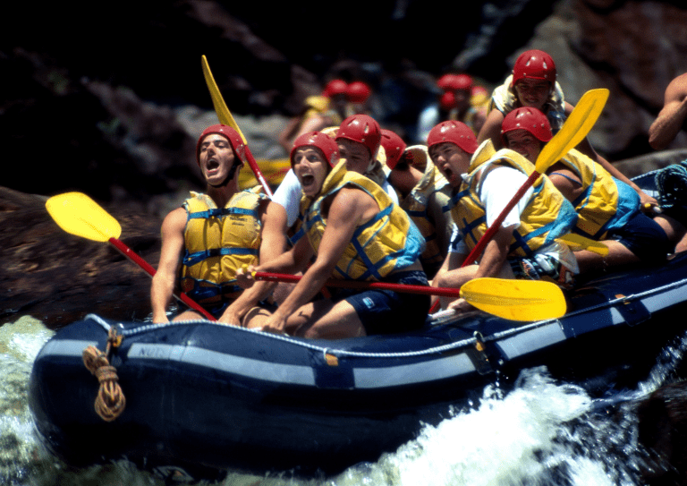 Groupe en plein action de rafting sur une rivière tumultueuse.
