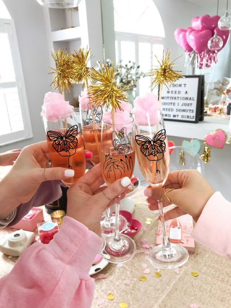 Mains levant des flûtes à champagne avec décorations de papillons.