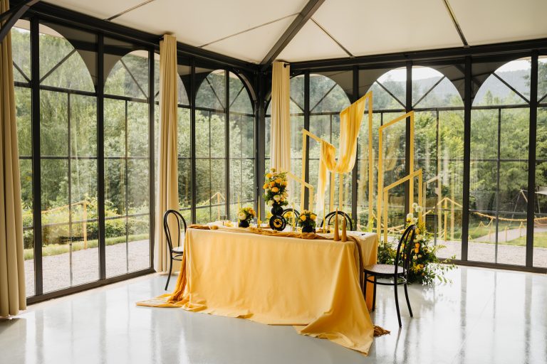 arche de cérémonie en fond dans une véranda avec vue sur la foret à noter que l'arche de ceremonie et dans les tons jaunes et ce marie avec la foret en fond