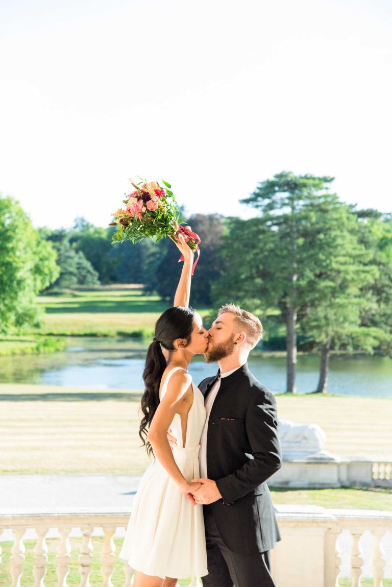 Couple s'embrassant tendrement, la mariée tenant le bouquet en l'air