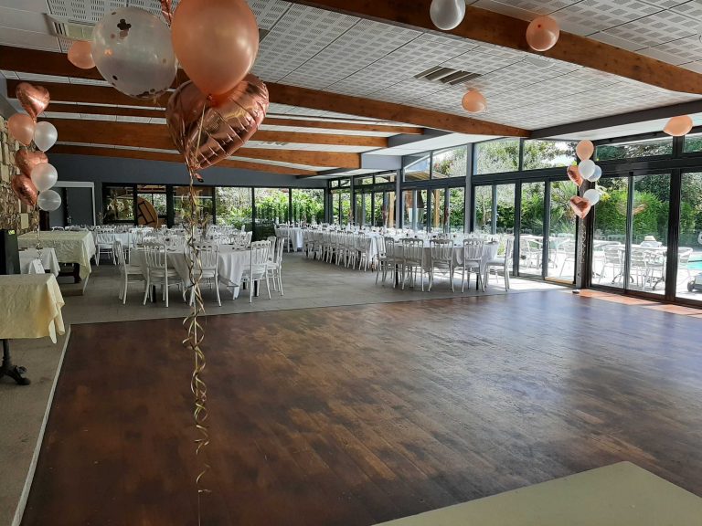 Salle de réception décorée de ballons et de tables élégamment dressées.