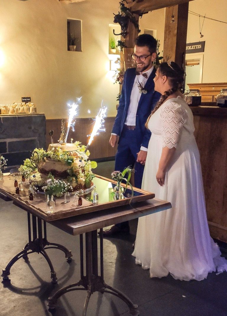 Mariés souriants coupant leur gâteau de mariage ensemble