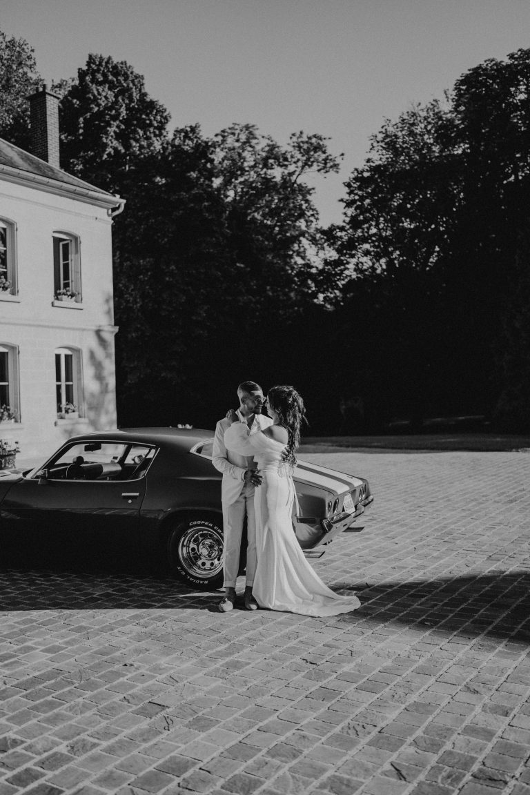 Mariés qui arrivent en voiture sport ancienne à leur mariage.