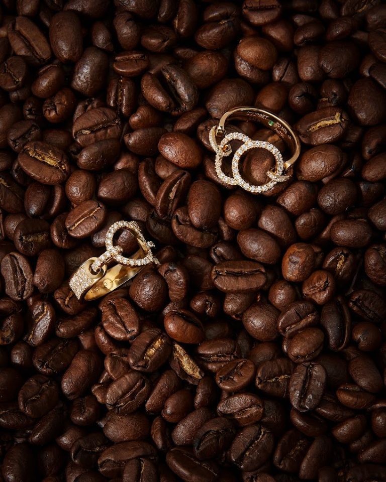 Bijoux Courbet étincelants posés sur des grains de café.