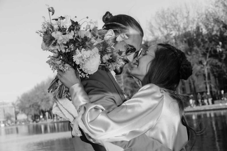 Couple s'embrassant passionnément en tenant un bouquet de mariage, en noir et blanc