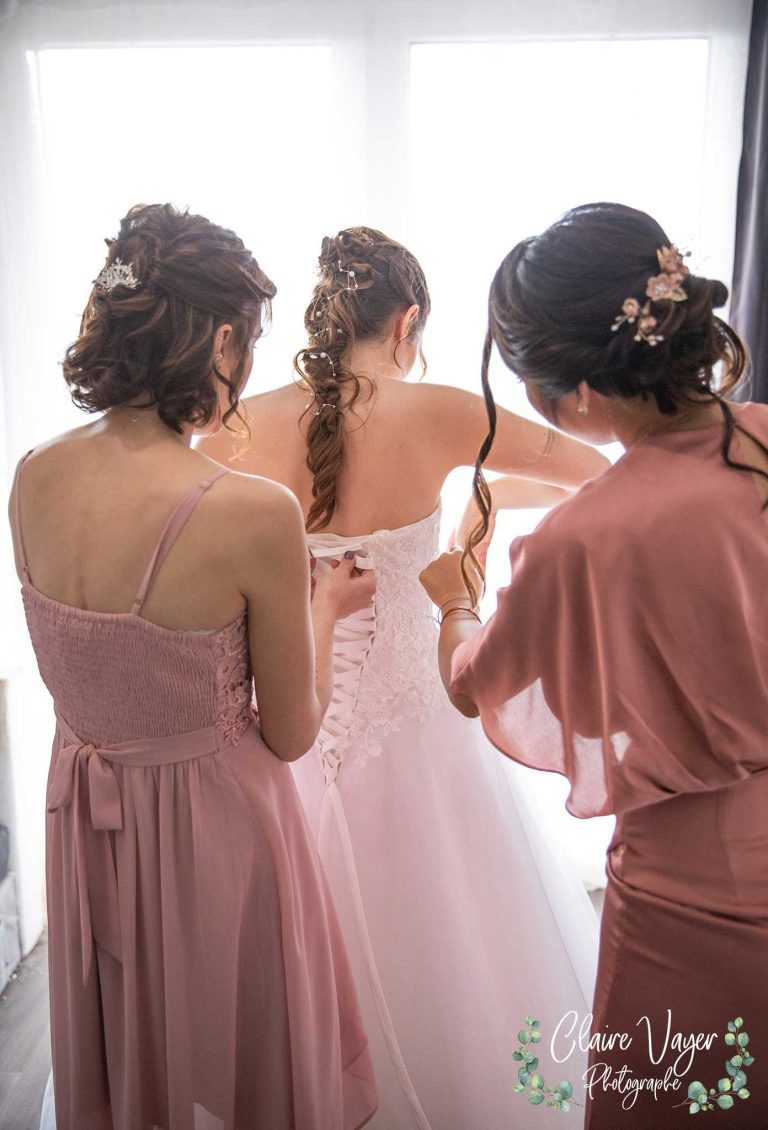 Assistants ajustant la robe de la mariée.