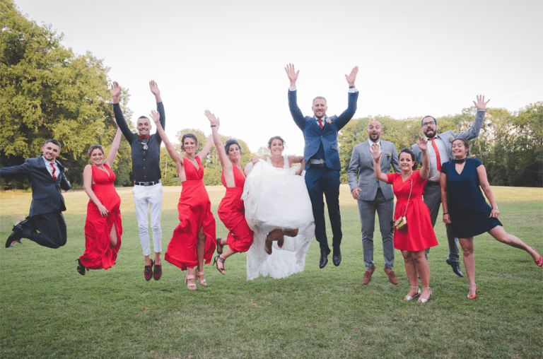 Groupe de mariés et amis sautant de joie en plein air.