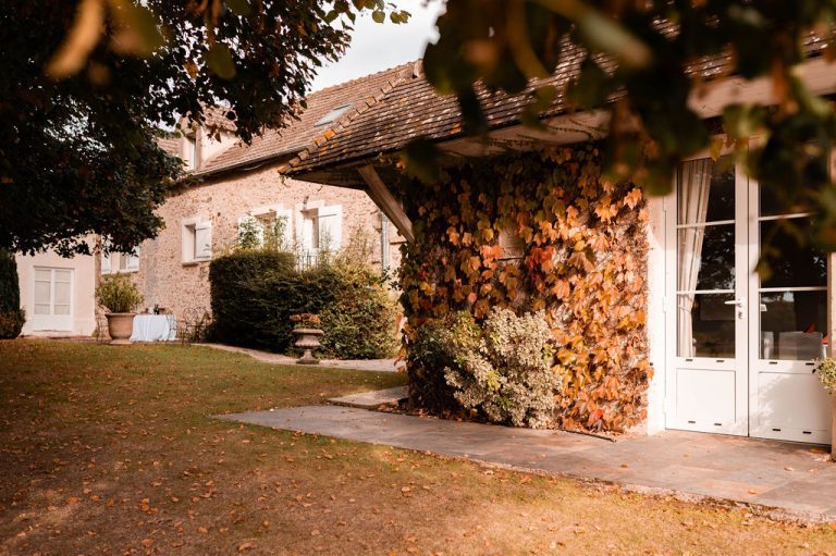 Ferme avec une façade en pierre ornée de feuillage d'automne.