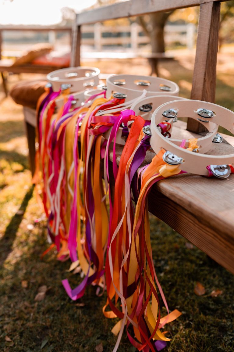 Tambourins décorés de rubans colorés alignés sur un banc en bois.