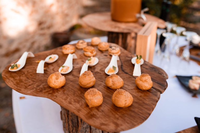 Table de bois avec une sélection de canapés et desserts légers, évoquant une ambiance bohème chic.