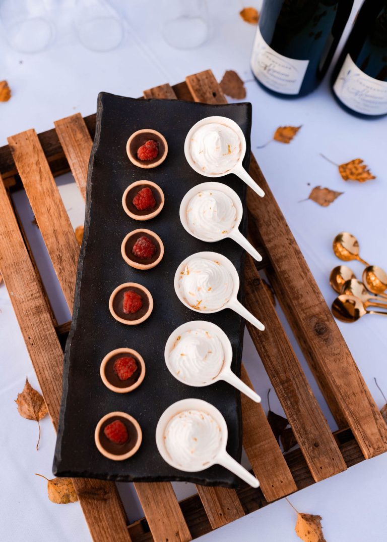 Assortiment de mignardises sur une ardoise noire, présentées de manière artistique.