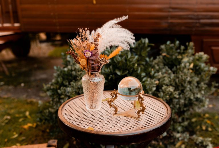 Composition florale bohème posée sur une table, avec une boule de cristal.