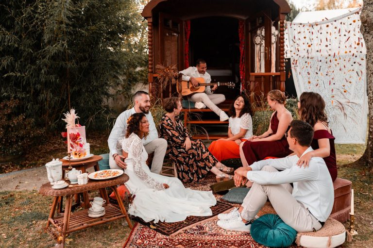 Groupe d'amis riant et profitant d'une performance musicale près d'une roulotte décorée.