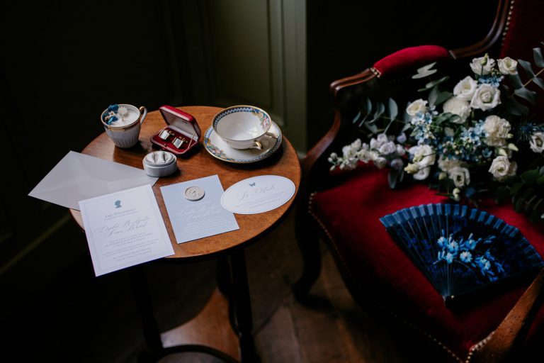 Table ronde avec invitations de mariage, bouquet, et accessoires élégants.