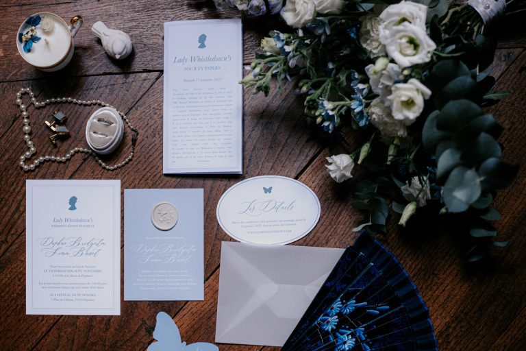 Éléments de papeterie pour mariage avec fleurs et accessoires sur une table en bois.