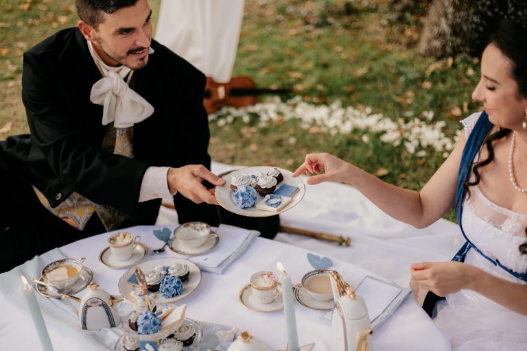 Mariés partageant des pâtisseries lors d'un goûter inspiré de Bridgerton en plein air.