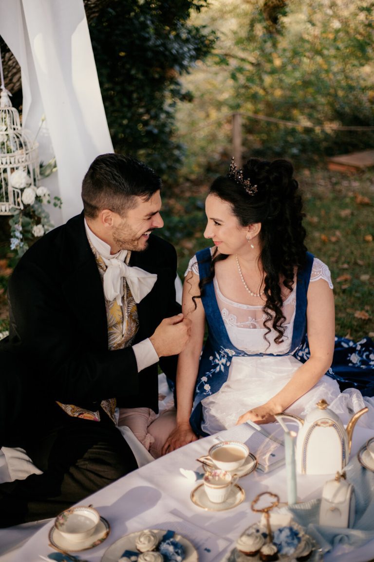 Jeunes mariés partageant une plaisanterie privée, assis à une table de thé thème Bridgerton.