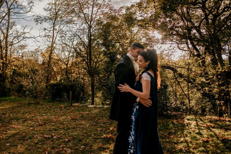 Couple enlacé dans un cadre naturel lumineux, évoquant une intimité romantique lors d'un mariage inspiré de l'époque de la Régence.