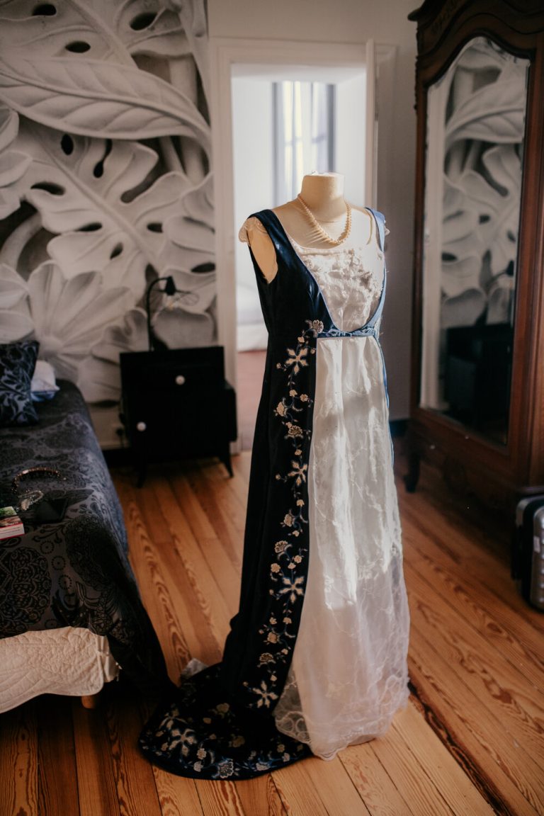 Robe de mariée élégante sur mannequin avec collier de perles, dans une chambre chic.