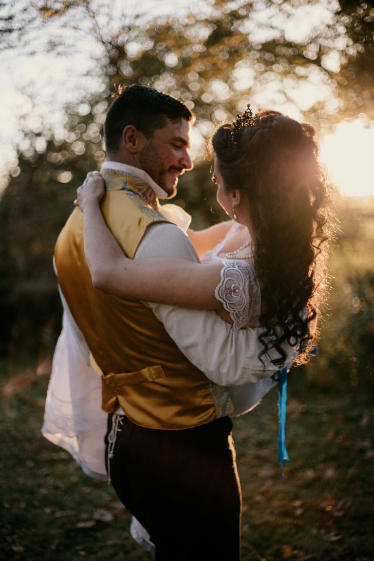 Couple échangeant une étreinte tendre sous la lumière du coucher de soleil, mariage thème Bridgerton.