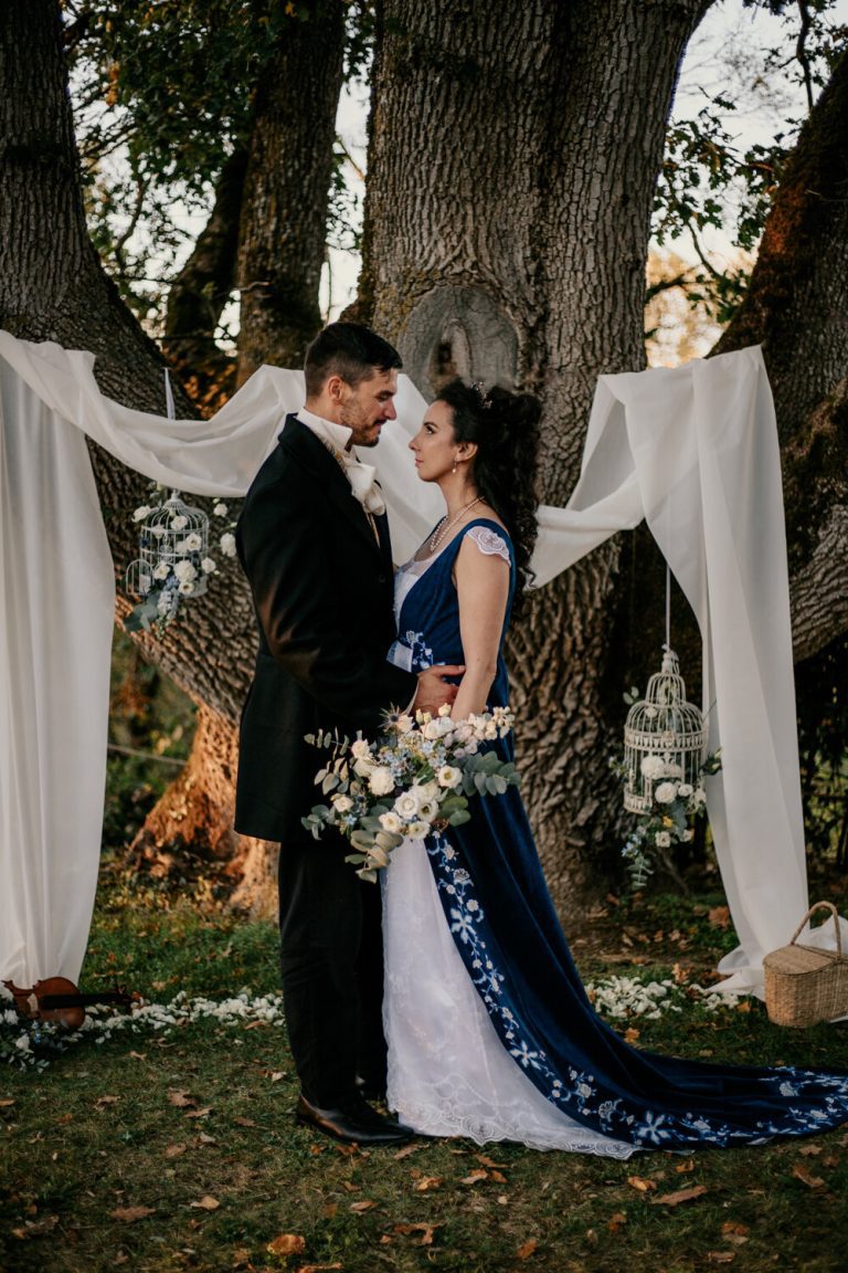 Mariés échangeant un regard complice sous des voiles blancs suspendus à un arbre, avec une décoration florale et des lanternes.