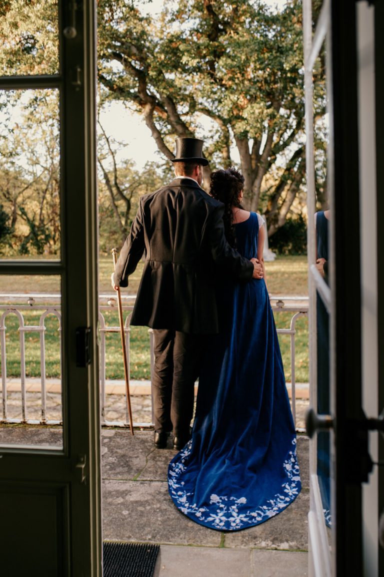 Couple marié inspiré de Bridgerton posant sous des arbres avec des décorations élégantes.