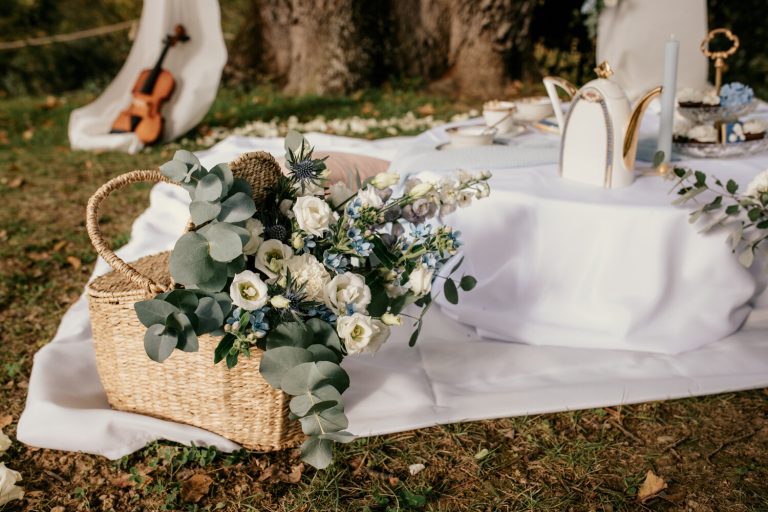 Décoration de table de mariage thème Bridgerton avec panier de fleurs, théière élégante et violon en arrière-plan