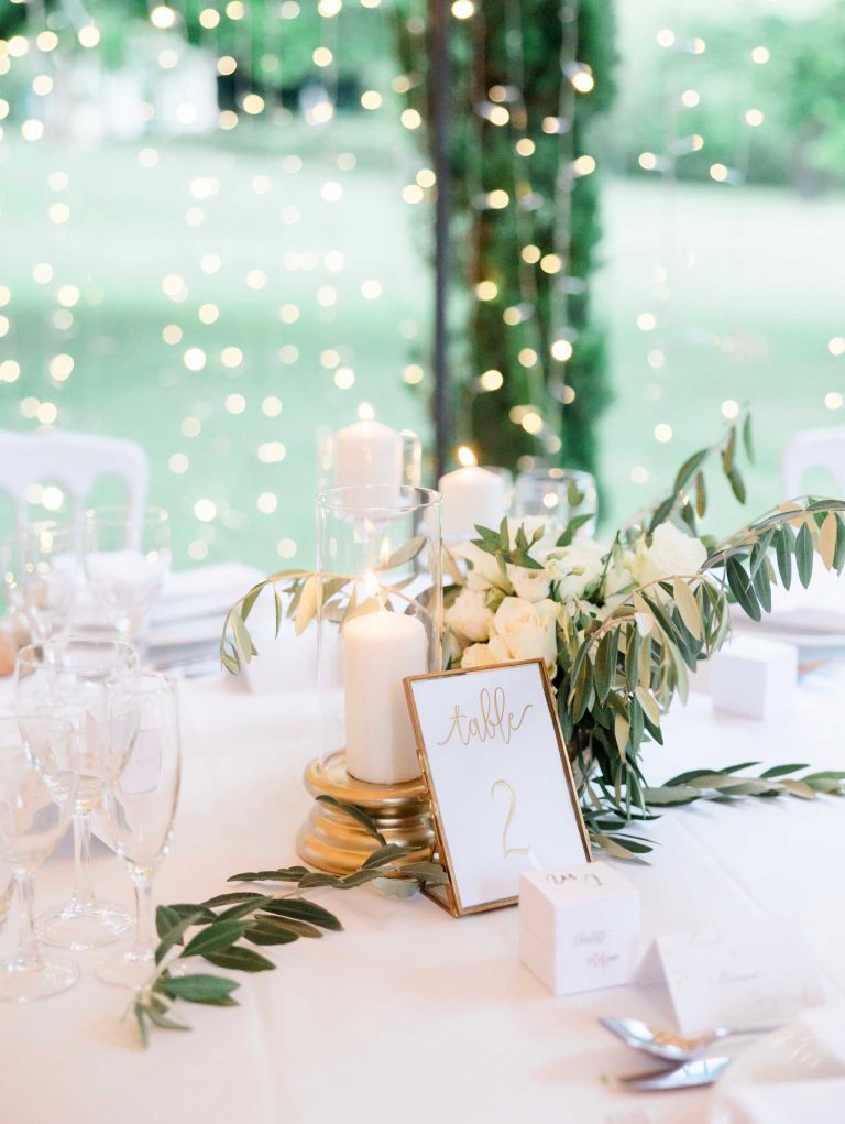 Décoration de table avec un bouquet de rose blanche des paillettes, des bougies et un numéro de table