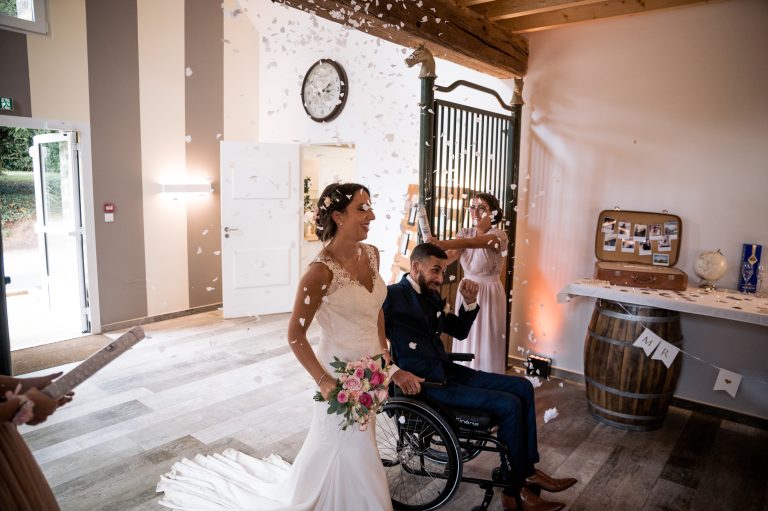 Mariés faisant leur entrée triomphale, marié en fauteuil roulant, sous une pluie de confettis