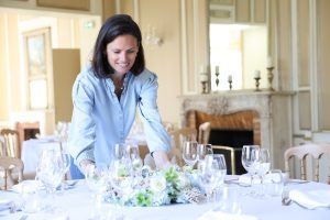 Anne-Sophie installe une décoration florale sur une table de réception dans un manoir de mariage élégant.