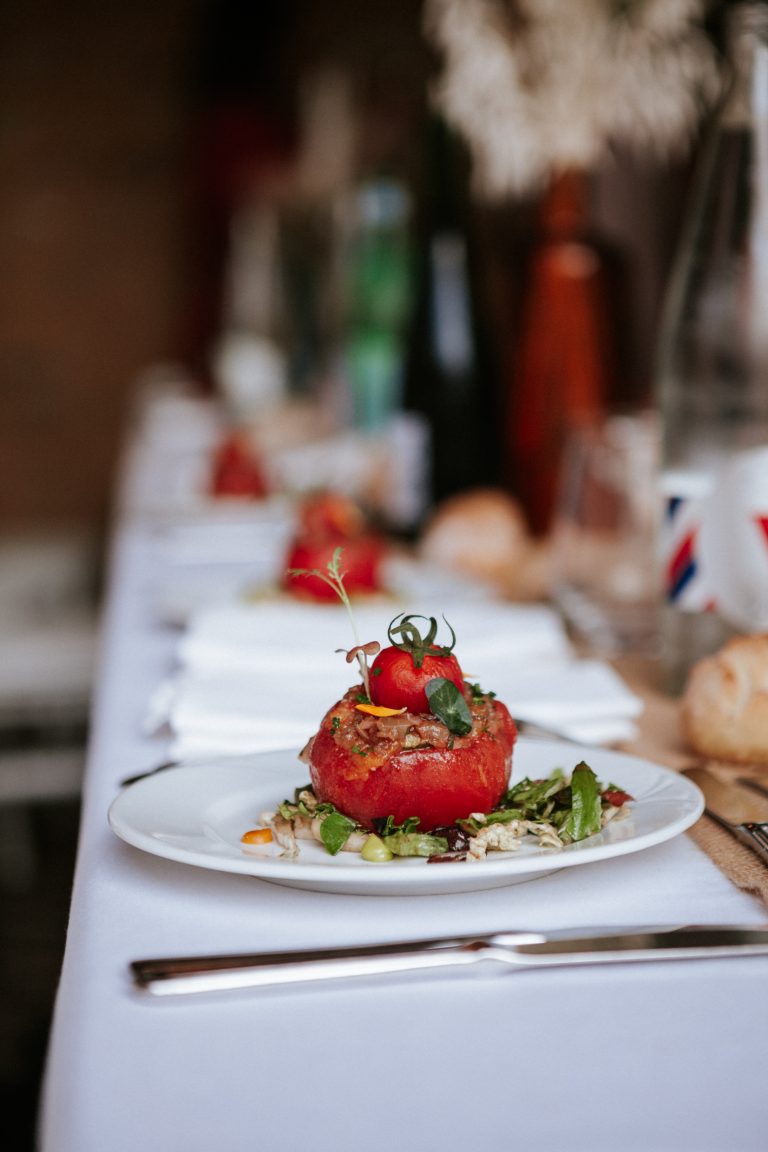 Entrée composée d’une tomate farcie servie sur lit de salade, dressée avec soin sur une table de mariage.