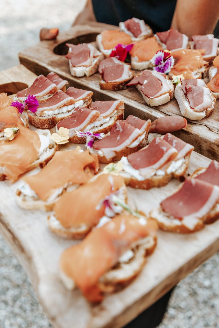 Plateaux de toasts garnis de magret de canard et de saumon fumé, décorés de fleurs comestibles, prêts à être servis.