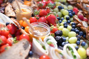 Gros plan sur un plateau coloré composé de fruits frais, wraps, dips maison et crackers, présenté de manière généreuse et estivale.