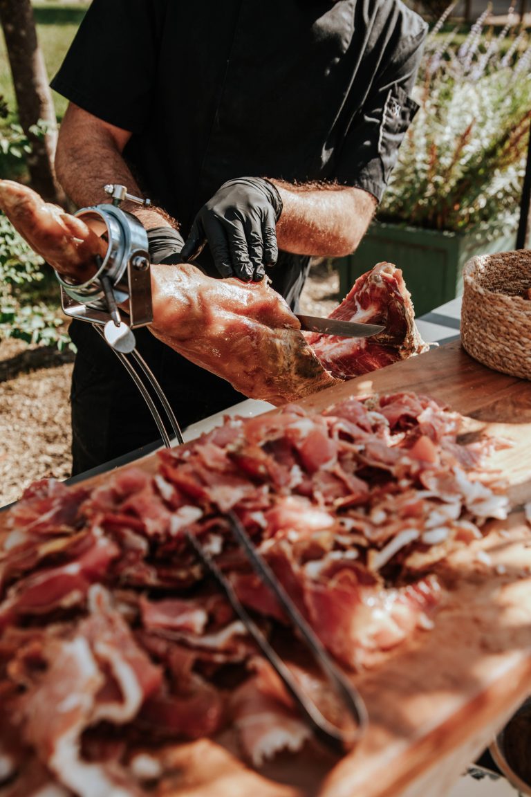 Découpe de jambon ibérique par un traiteur lors d’un vin d’honneur, une prestation qui fait grimper le prix traiteur mariage.
