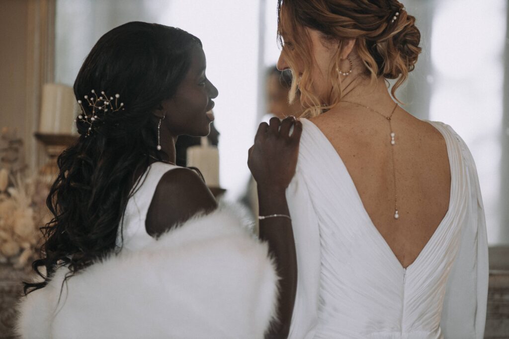 Deux mariées avec bijoux et dos nus, ambiance élégante et chaleureuse.