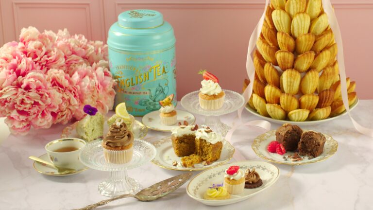 Table de desserts élégante avec cupcakes, muffins, madeleines en pièce montée, et boîte de thé anglais turquoise.