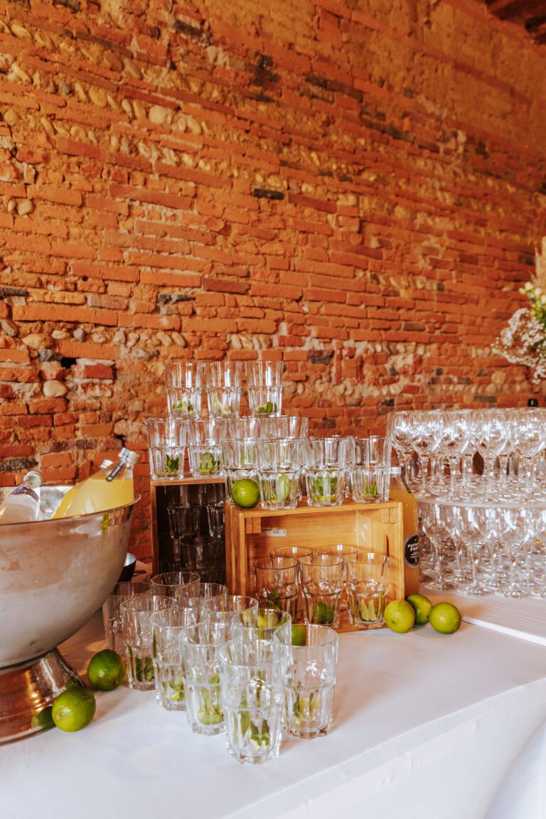 Verres à mojito prêts à être servis sur une table de mariage, accompagnés de citrons verts et de feuilles de menthe.